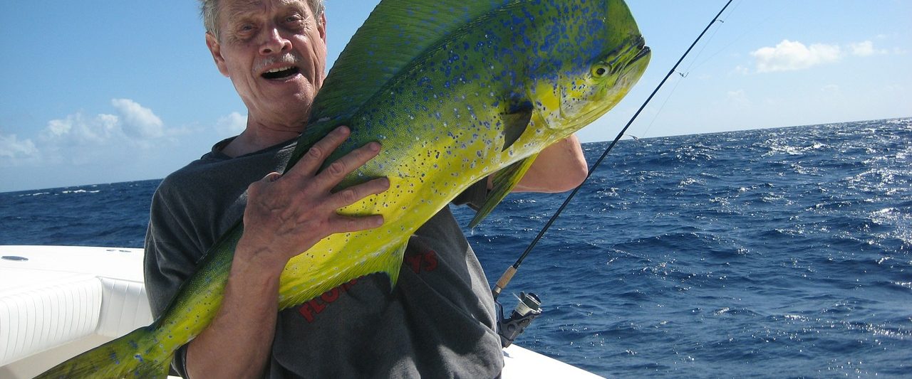 photo of a man holding a large fish on a boat