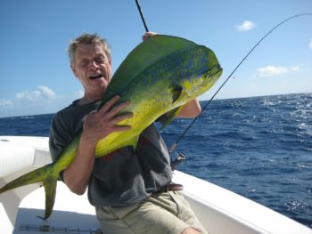 photo of a man holding a large fish on a boat