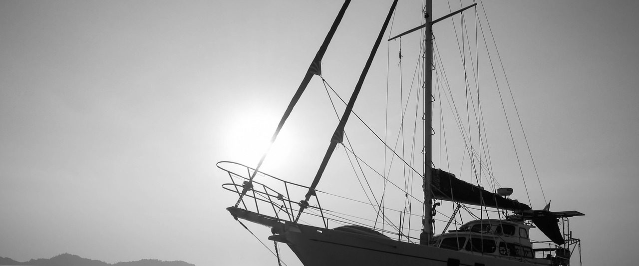 photo of a sail boat against ocean and sunset