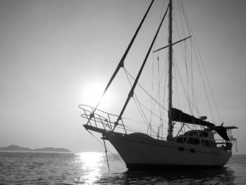 photo of a sail boat against ocean and sunset